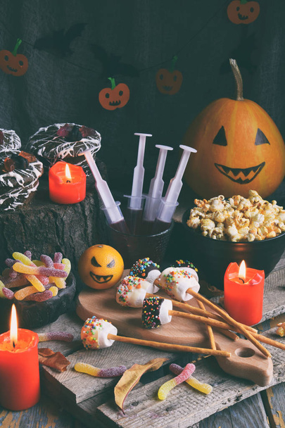 Impreza Halloween trick lub leczenia. Zabawny pyszne słodycze i dyni na podłoże drewniane - babeczki, babeczki, marshmallows, popcorn, sok, galaretki, candy - Zdjęcie, obraz