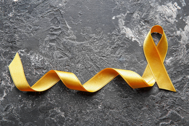 Golden ribbon on grunge background. Children cancer concept - Фото, изображение