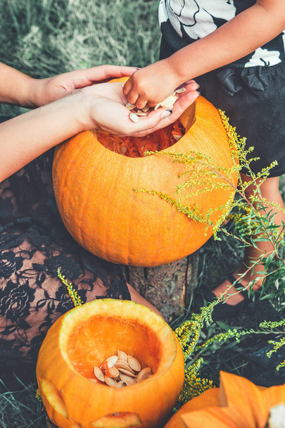 lähikuva naisen ja lapsen käsissä vetää siemeniä ja kuitumateriaalia kurpitsan ennen veistämistä Halloween. Jack-o-lyhty. Sävytetty kuva. tytär ja äiti
 - Valokuva, kuva
