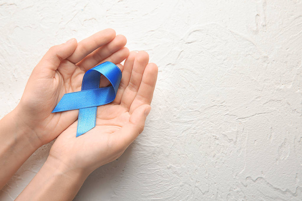 Mujer sosteniendo cinta azul sobre fondo claro. Concepto de cáncer
 - Foto, imagen