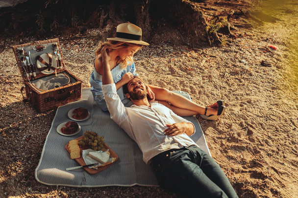 Beautiful couple enjoying picnic time on the sunset. - Valokuva, kuva