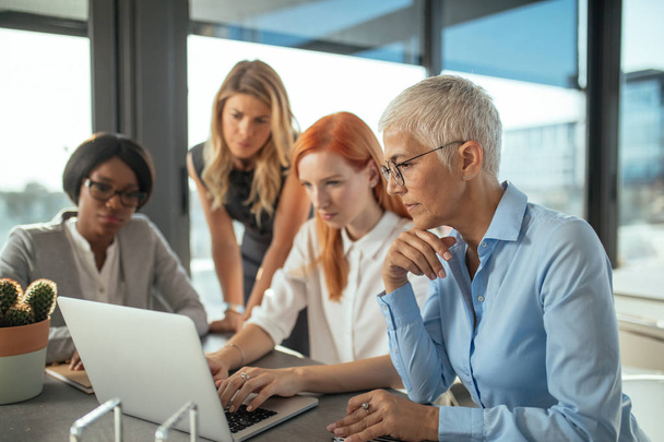 Group of female businesswomen working together on a laptop. - Zdjęcie, obraz