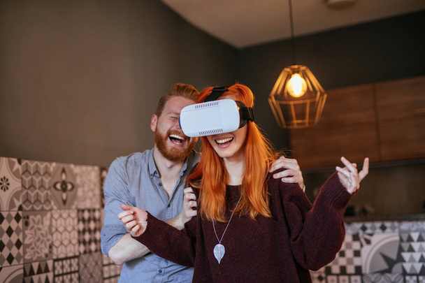 Young couple having fun at home with virtual reality headset. - Zdjęcie, obraz