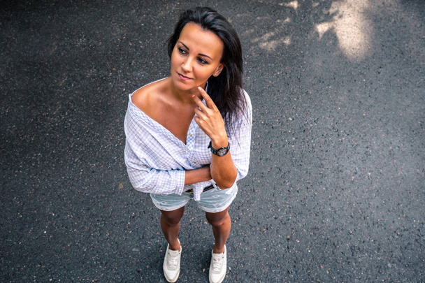 Contrast portrait of the top brunette. A middle-aged woman in a shirt and shorts. - 写真・画像