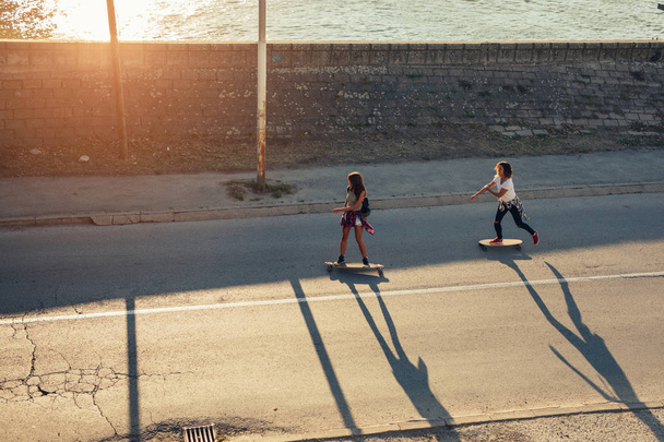 High angle of two friends driving long board on the road. - Fotografie, Obrázek