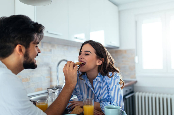 Portrait of a handsome young man feeding his girlfriend at breakfast. - Photo, image