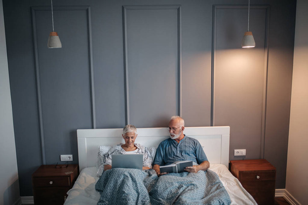 A senior couple both engaging in their morning activities. - Photo, image
