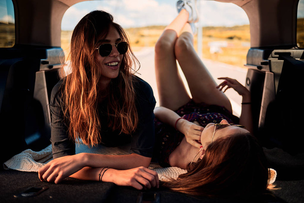 Twee meisjes in de kofferbak liggen en rusten van de rijbevoegdheid. - Foto, afbeelding