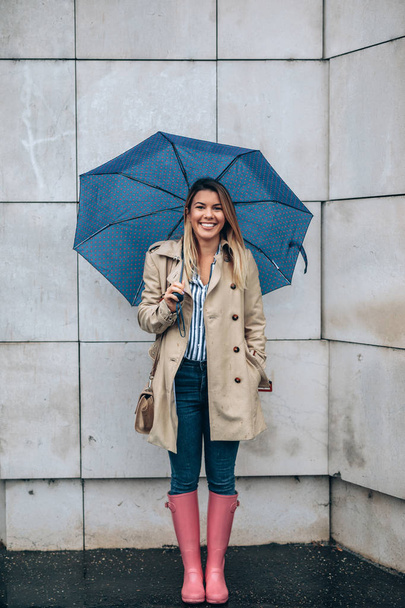 Full length portrait of a young woman holding an umbrella outdoors. - Fotoğraf, Görsel