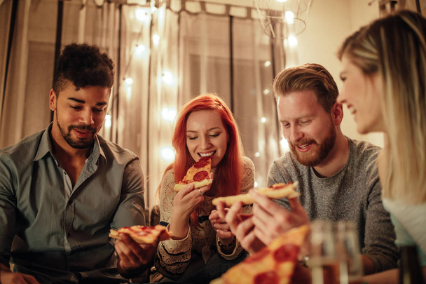 A group of friends eating a delicious pizza together. - Photo, image