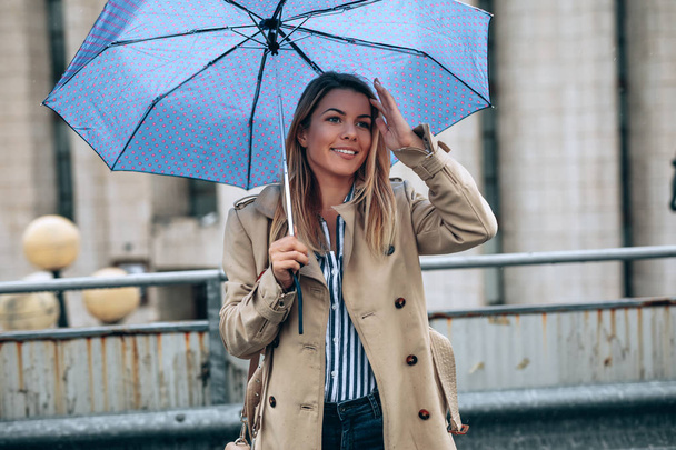 Portrait of young woman with an umbrella outdoors. - Фото, изображение