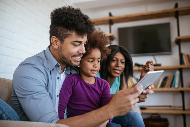 African american parents teaching their daughter how to use digital tablet at home. - Φωτογραφία, εικόνα