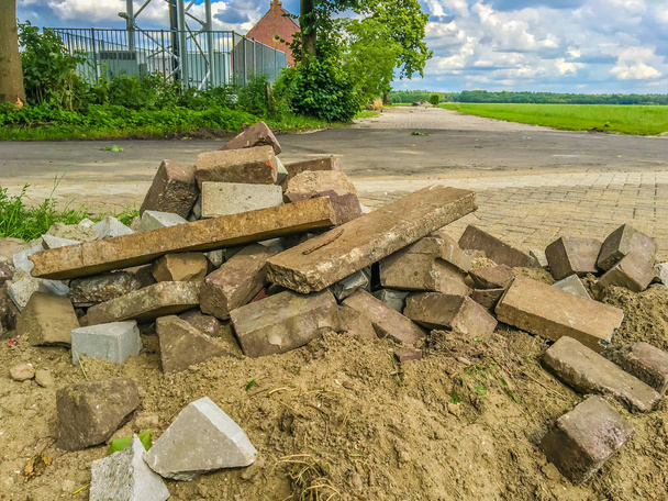 różne kształty kamieni cegły ułożone na stertę piasku z widokiem na krajobraz - Zdjęcie, obraz