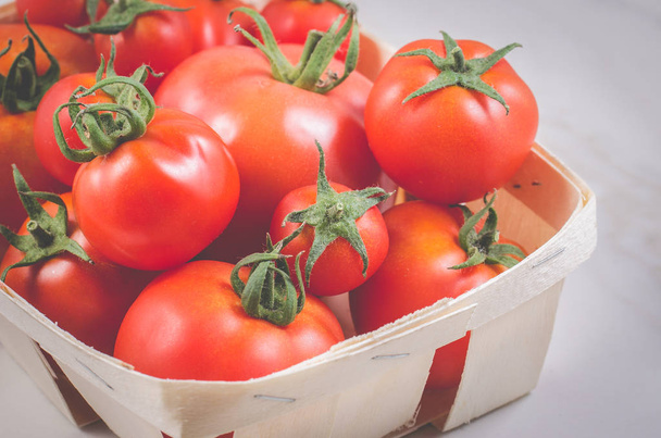 tomatoes in a wattled basket/tomatoes in a wattled basket on a white background, selective focus - Φωτογραφία, εικόνα
