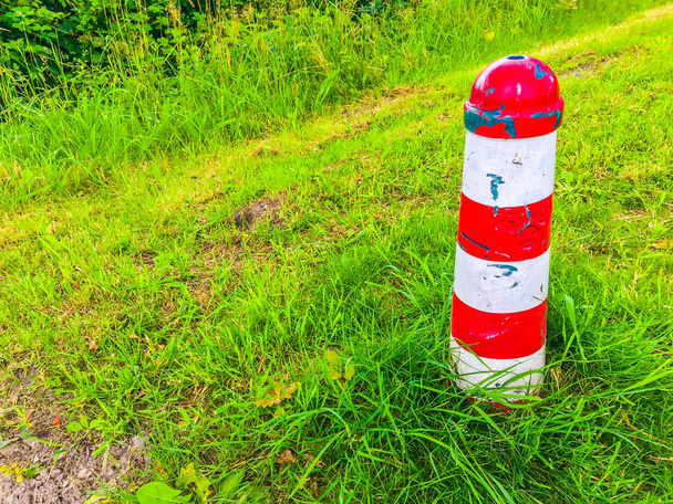 pólo de referência listrado vermelho e branco em uma paisagem de grama
 - Foto, Imagem