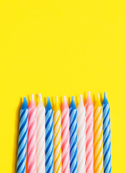 Colorful candles on yellow background.  - 写真・画像