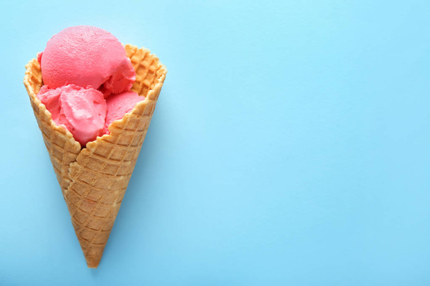 Waffle cone with delicious strawberry ice-cream on color background - Фото, зображення