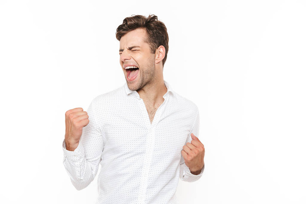 Photo of happy man 30s rejoicing and clenching fists isolated over white background - Φωτογραφία, εικόνα