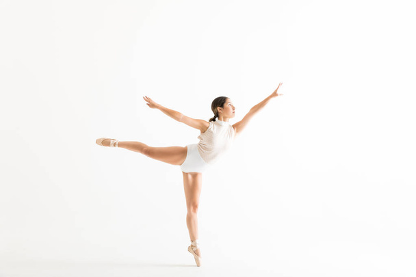 Повна довжина витонченої балерини робить позу балету під назвою арабеска на білому тлі
 - Фото, зображення