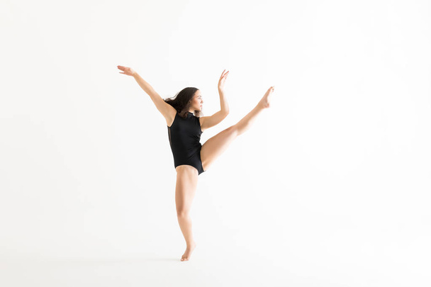 Comprimento total de intérprete feminina em cotovelo preto praticando movimentos de balé sobre fundo branco
 - Foto, Imagem
