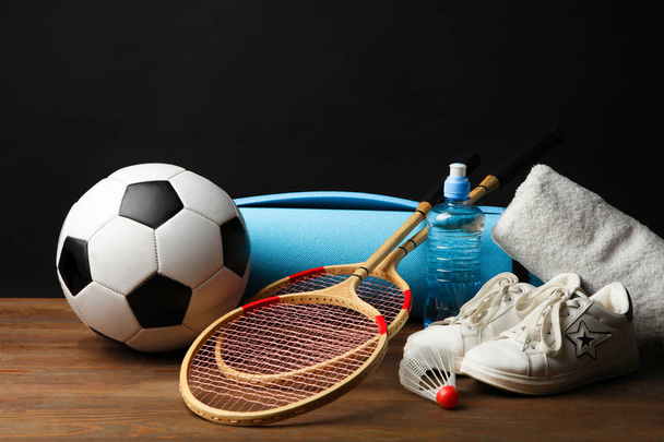 Различные спортивные средства на деревянном столе на черном фоне. Концептуальный спорт
. - Фото, изображение