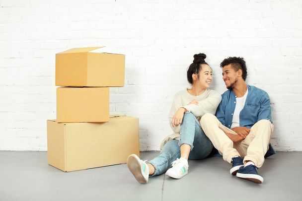 Šťastný pár interracial položenou na podlaze krabičkách v pokoji. Stěhování do nového domu - Fotografie, Obrázek