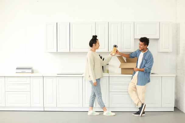 開梱幸せの異人種間のカップルは、キッチンのボックスです。新しい家に移動 - 写真・画像