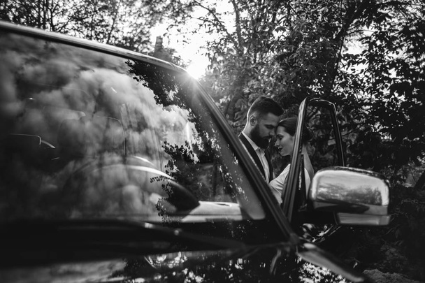 Newlyweds near a black car for a walk in the forest - Fotografie, Obrázek