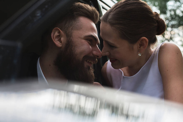 Férj és feleség nevetni közelében a fekete autó - Fotó, kép