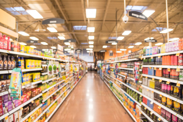 Motion blurred customer shopping for natural coffee, tea, water, bottled tea, energy drinks aisle in store at Houston, Texas, US. Wide view supermarket shelves, variety of products display bokeh light - Photo, Image