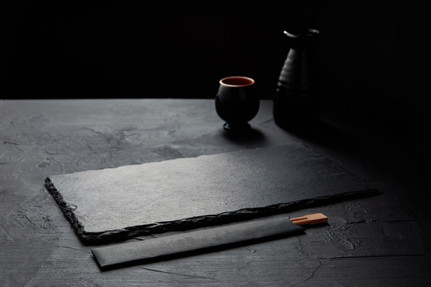 empty black slate board, chopsticks, jug and mug - Photo, Image