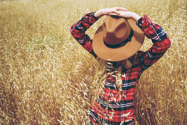 Jovem mulher loira usando chapéu marrom posando no campo amarelo do trigo  - Foto, Imagem
