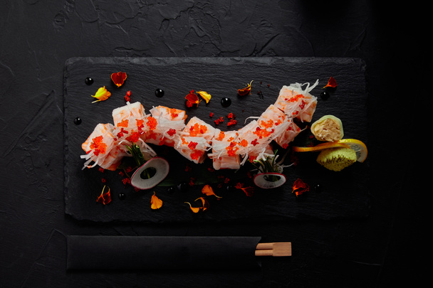 vista dall'alto di yummy roll in mamenori con gamberi, salmone e avocado su tavola di ardesia e bacchette
  - Foto, immagini
