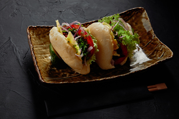 close-up view of delicious spicy pork buns with vegetables on plate    - Photo, Image