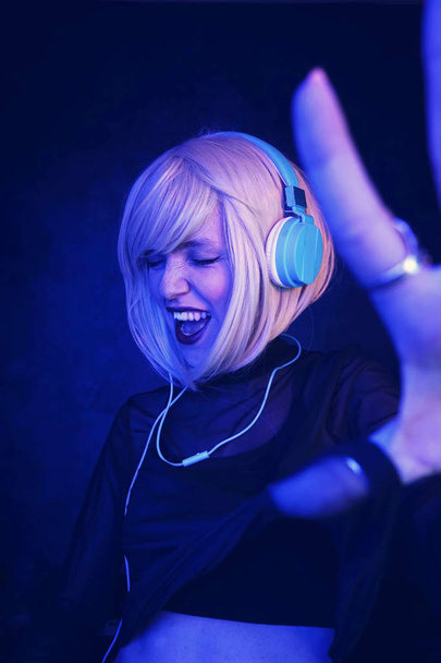 Colorful portrait in blue and dark lights of young DJ woman enjoying a night party                    - Valokuva, kuva