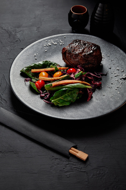 close-up view of gourmet roasted meat in Teriyaki sauce with grilled cherry tomatoes, red cabbage and leaves of spinach, baby corn and kumquat  - 写真・画像