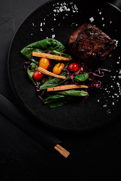 close-up view of juicy beef in Teriyaki sauce with grilled cherry tomatoes, red cabbage and leaves of spinach, baby corn and kumquat - Photo, Image