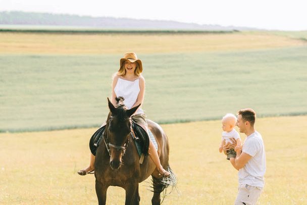 A young family have a fun in the field. Parents and child with a horse - Fotoğraf, Görsel