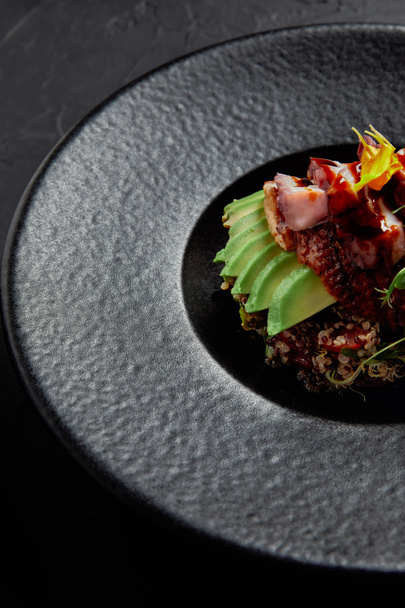 close-up view of delicious traditional japanese dish with seafood, avocado and herbs on black plate - Photo, Image