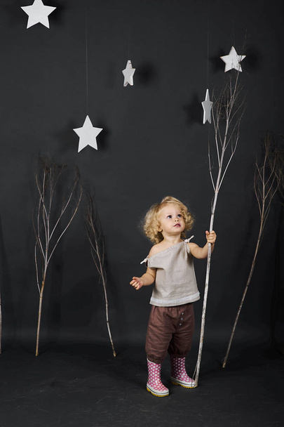funny curly little girl on a grey background with trees - Foto, imagen