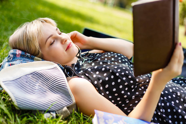 Nainen makaa tai rentouttava vihreä ruoho käsittelyssä kirja kesällä tai keväällä, ylhäältä
 - Valokuva, kuva