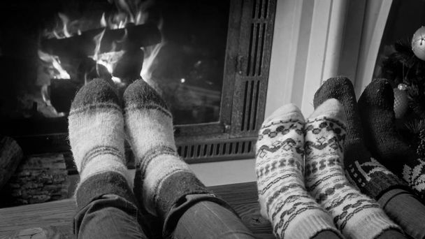 Fekete-fehér kép pár gyapjú kötött zokni pihentető mellett a kandalló otthon - Fotó, kép