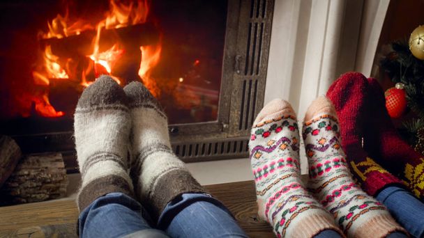 Closeup photo of three persons in woolen socks warming at the fireplace - Photo, Image