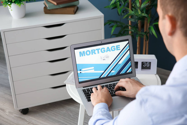 Man using laptop to pay mortgage loan online in office - Foto, Imagem