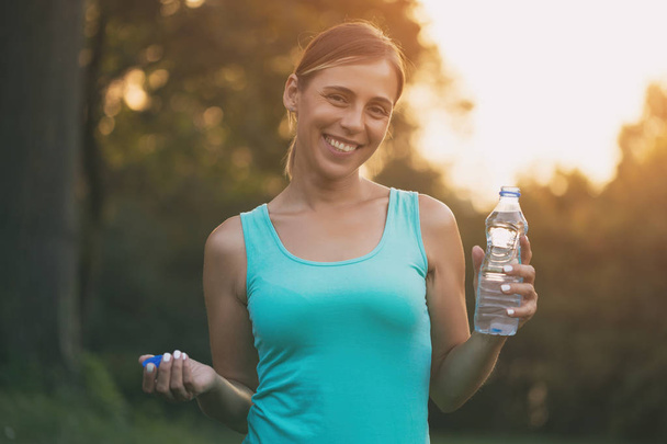 Beautiful sporty woman drinking water during exercise.Image is intentionally toned. - Фото, изображение