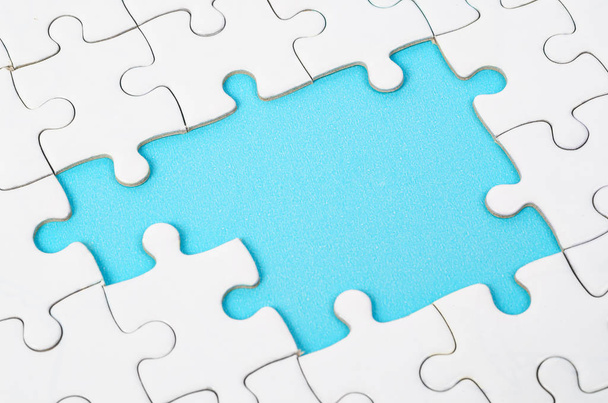 Onvoltooide witte puzzelstukjes op blauwe achtergrond - Foto, afbeelding