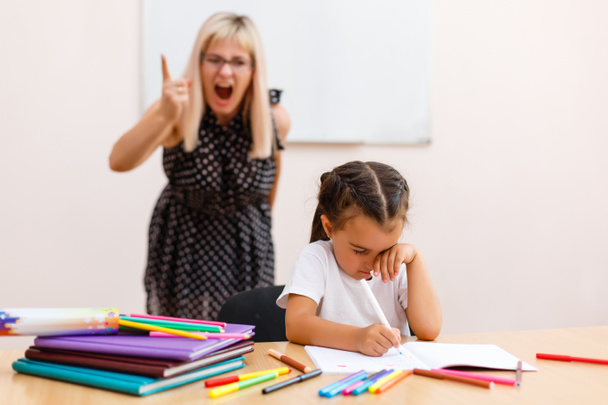 先生はほとんどの女子高生に悲鳴します。少女は教室の机で悲しい - 写真・画像