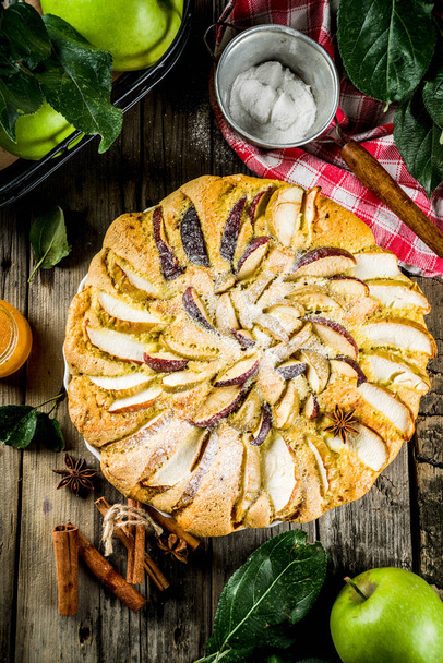 Homemade apple biscuit pie, sponge cake with red and green apples, on a wooden rustic table, with apples and leaves. Top view copy space - Photo, Image