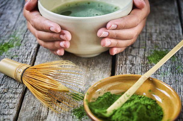 Girls hands holding matcha tea in special matcha tea bowl with bamboo spoon and whisk - Fotoğraf, Görsel