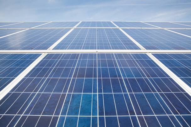 Napelemek a napos égbolttal. Kék napelemek. a megújuló energiaforrásokra vonatkozó fotovoltaikus modulok háttere. - Fotó, kép